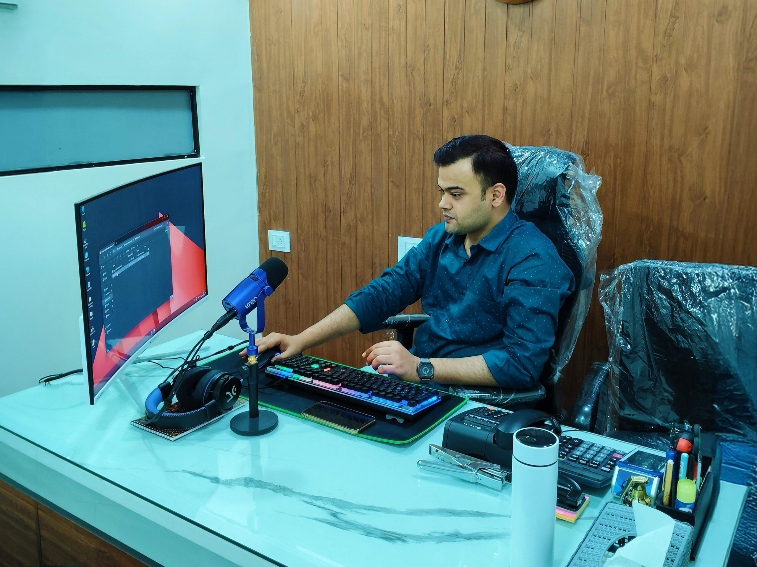 a man sitting at a desk with a computer keyboard and a microphone